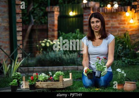 Mitte Alter Frau Blumen Pflanzen im Hinterhof Stockfoto