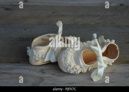 Vintage Baby Schuhe mit Rüschen und Blumen auf einem natürlichen Holz- Hintergrund Stockfoto