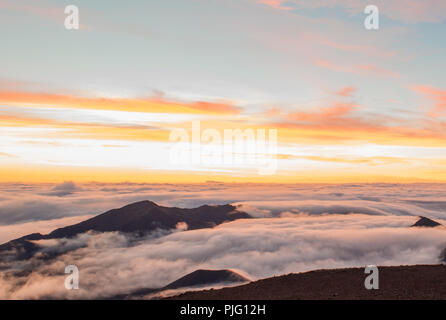 Eine flammende Morgen Sonne über eine Verkleidung von Wolken in den Krater des Haleakala, einem schlafenden Vulkan auf der Insel Maui, Hawaii Stockfoto