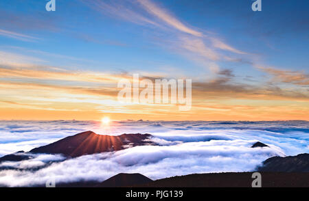 Eine flammende Morgen Sonne über eine Verkleidung von Wolken in den Krater des Haleakala, einem schlafenden Vulkan auf der Insel Maui, Hawaii Stockfoto