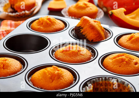 In der Nähe von frisch gebackenen hausgemachten süßen Kürbis Muffins in einer Backform auf einem rustikalen Holztisch, leckere Herbst Dessert für Halloween oder potluck Stockfoto