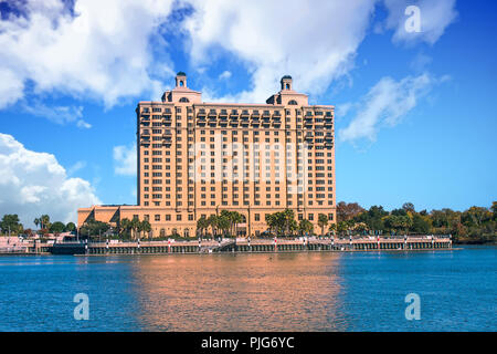 Eine massive braun Hotel Rising in den klaren blauen Himmel auf der Bank eines breiten ruhigen Fluss Stockfoto