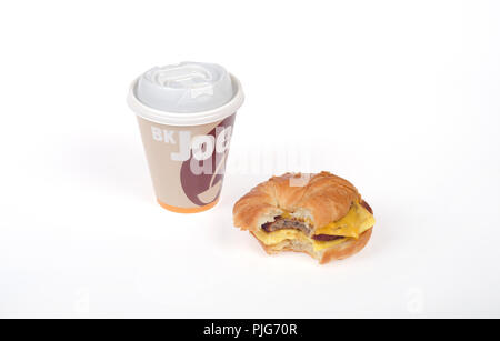 Burger King Würstchen, Eier und Käse croissan', oder Croissant Sandwich mit einem Bissen genommen und eine Tasse Kaffee mit der Bezeichnung BK Joe Stockfoto