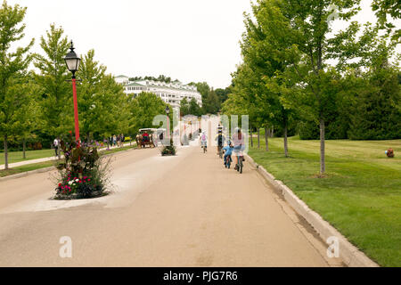 Touristen auf dem Fahrrad über die historische Mackinac Island im oberen Mittelwesten, USA. Keine Autos sind auf der Insel nicht erlaubt. Pferde und Fahrräder nur. Stockfoto