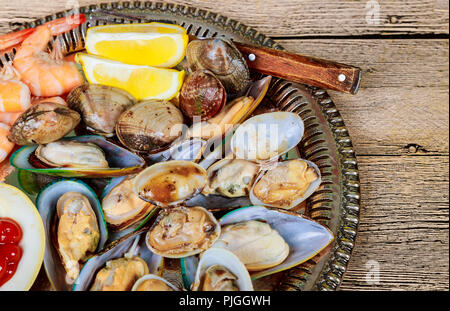 Wanne aus Metall mit grünen Muscheln in Soße über und Zitrone Stockfoto