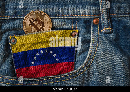 Golden BITCOIN (BTC) cryptocurrency in der Tasche der Jeans mit der Flagge der Bolivarischen Republik Venezuela auf Jeans Denim Textur. Stockfoto