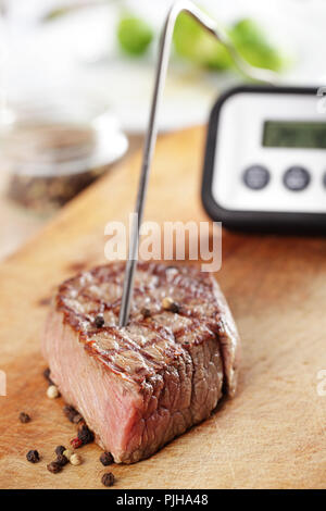 Gegrilltes Steak auf dem Schneidbrett mit Temperaturregler innen Stockfoto