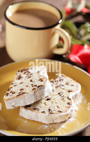 Stollen mit Rosinen closeup gegen die Tasse Kaffee mit Milch und Weihnachten Kranz Stockfoto