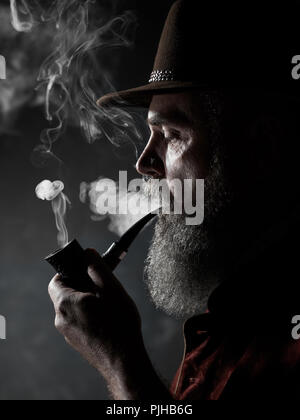 Dramatische Portrait von älteren Mann in hat das Rauchen von Tabak. Profil anzeigen von österreichischen, Tiroler, Bayerische alter Mann Stockfoto