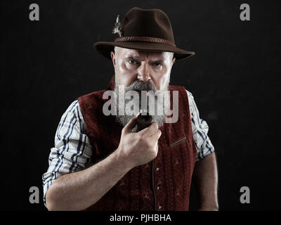 Dramatische Portrait von grauen Bärtigen älteren Mann in hat Tabak Pfeife. Blick auf die österreichischen und Tiroler, Bayerische alter Mann in nationaler Tracht im Retro-Stil. Stockfoto