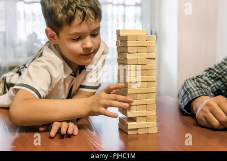 Vater und Sohn spielen jenga Spiel zu Hause. Großvater und Enkel spielen mit Blöcke auf einem Holztisch. einen Turm bauen. Stockfoto