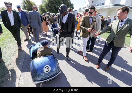 Ein junger Mann fährt mit seinem Austin J40 Pedal Car vergangenen Rennen goers am ersten Tag des Goodwood Revival im Goodwood Motor Circuit, Chichester. Stockfoto