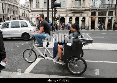 Fahrrad Rikscha Fahrer und Touristen im Verkehr in der Nähe der Houses of Parliament in Westminster auf der Bridge Street in London UK KATHY DEWITT Stockfoto