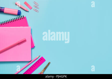Rosa mädchenhafte Schulmaterial, Hefte und Stifte auf druckvolle Blau. Ansicht von oben, flach. Kopieren Sie Platz. Stockfoto