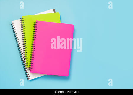 Bunte mädchenhafte Schulmaterial, Hefte und Stifte auf druckvolle Blau. Ansicht von oben, flach. Kopieren Sie Platz. Stockfoto