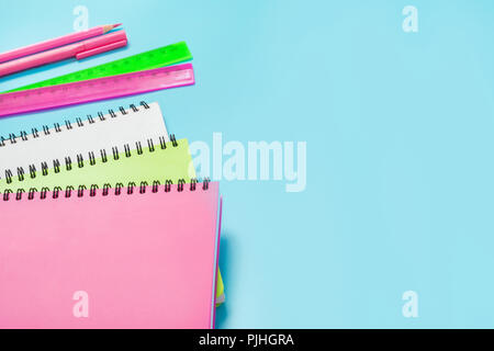 Bunte mädchenhafte Schulmaterial, Hefte und Stifte auf druckvolle Blau. Ansicht von oben, flach. Kopieren Sie Platz. Stockfoto