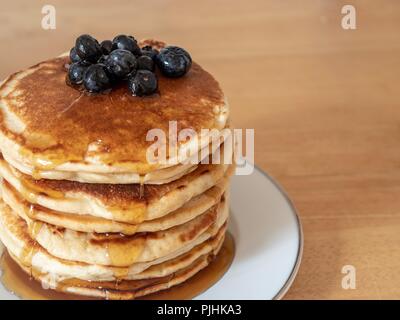 Einen großen Stapel Pancakes mit Ahornsirup und blaue Beeren bedeckt Stockfoto