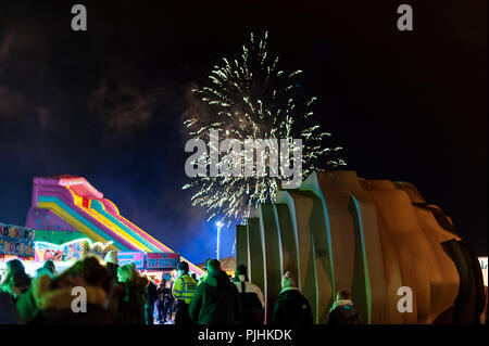 Ein Feuerwerk explodiert in den Nachthimmel als Menschen besuchen einen Vergnügungspark auf der Promenade in Littlehampton, West Sussex, UK. Stockfoto