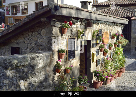 Restaurant La Casuca del Puente, durch eine Brücke über den Fluss Deva in Potes, Picos de Europa mit einer attraktiven Darstellung von Blumen und Menüs Stockfoto