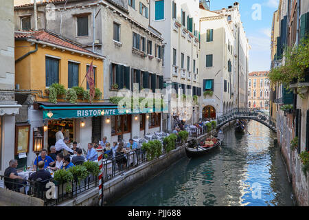 Venedig, Italien - 13 AUGUST 2017: Restaurant mit Bürgersteig Tische mit Menschen in Venedig, Canal mit Gondel in Italien Stockfoto