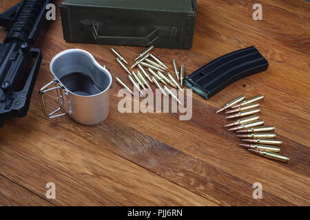 Sturmgewehr und Tasse Kaffee auf hölzernen Tisch Hintergrund Stockfoto