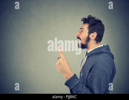 Seitenansicht des legerer Mann in Hoodie holding Finger bis in helle Idee auf grauem Hintergrund Stockfoto