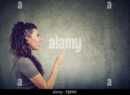 Seitenansicht der aufgeregten Frau mit Finger bis in helle Idee auf grauem Hintergrund Stockfoto