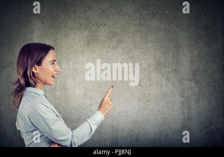 Seitenansicht der aufgeregten Frau mit Finger bis in helle Idee auf grauem Hintergrund Stockfoto