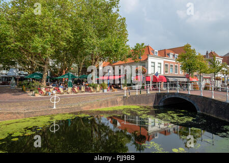 Sonnige Terrasse mit Menschen genießen die Sonne im Zentrum der Altstadt von Delft, Niederlande. Stockfoto