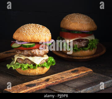 Große Burger mit zwei gebratene Koteletts, Käse und Gemüse in einer Runde Weizenmehl bun Stockfoto
