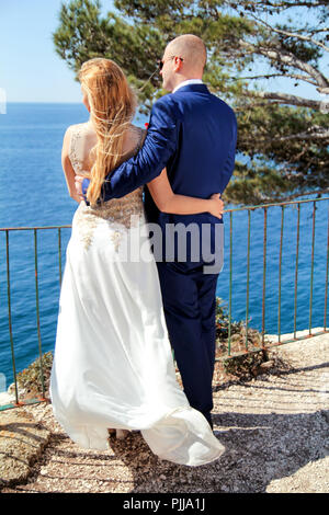 Hochzeit. Glückliches Paar tag Hochzeit. Schöne Braut und Bräutigam am Strand. Fröhliches Ehepaar stehend auf die Küste und das Meer beobachten. Hochzeit. Stockfoto