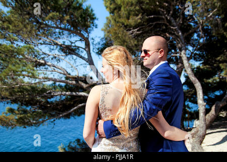 Hochzeit. Glückliches Paar tag Hochzeit. Schöne Braut und Bräutigam am Strand. Fröhliches Ehepaar stehend auf die Küste und das Meer beobachten. Hochzeit. Stockfoto