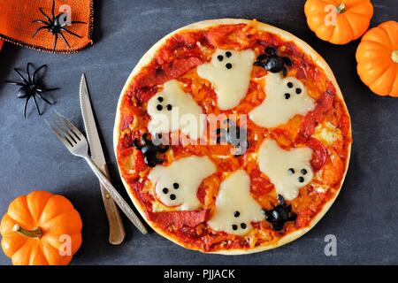 Halloween Pizza mit Gespenstern und Spinnen, oben genannten Szene mit Dekor auf schwarzem Hintergrund Stockfoto