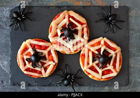 Halloween Spinnennetz mini Pizzas, Ansicht von oben auf einer Schiefertafel Server mit Spinnen Stockfoto