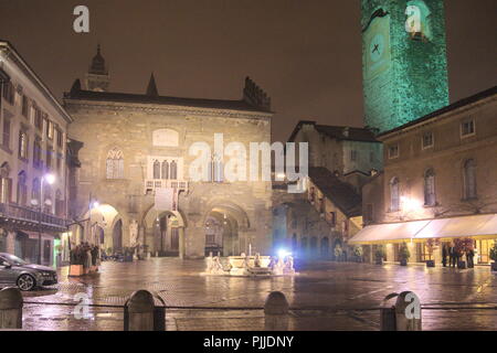 Italien, die historische Altstadt von Bergamo. Die Piazza Vecchia ist an einem regnerischen Winterabend beleuchtet Stockfoto