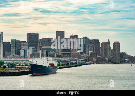 Boston Skyline von Boston Harbor gesehen - Blick auf die Stadt Boston und ein containerschiff von einem Kreuzfahrtschiff verlässt Boston Harbor Stockfoto