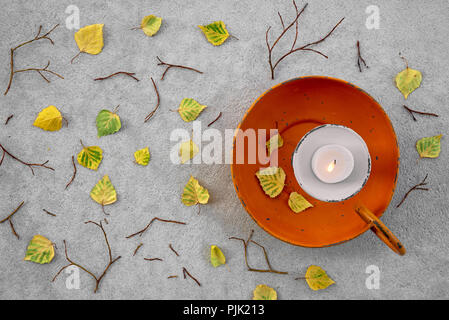 Blätter im Herbst und gemütliches Kerzenlicht auf grauem Beton Hintergrund. Stockfoto