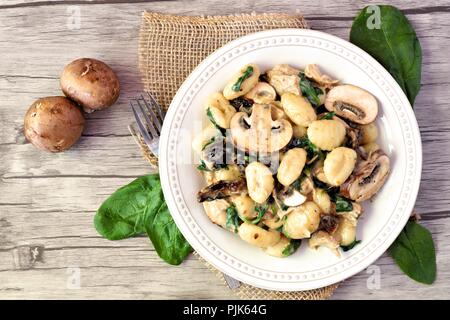 Gnocchi mit einem Champignon Sahnesauce, Spinat, Huhn und sonnengetrocknete Tomaten, vor Szene auf einem Holz Hintergrund Stockfoto