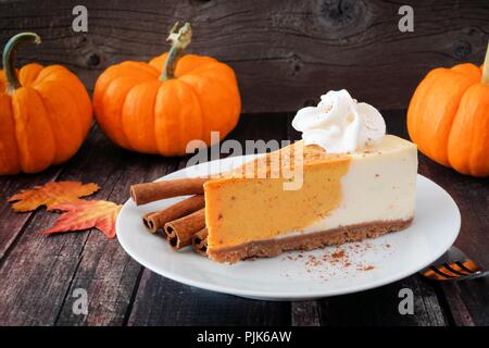 Schicht von Pumpkin Cheesecake mit Schlagsahne auf einem dunklen rustikalen, mit Holz Hintergrund Stockfoto