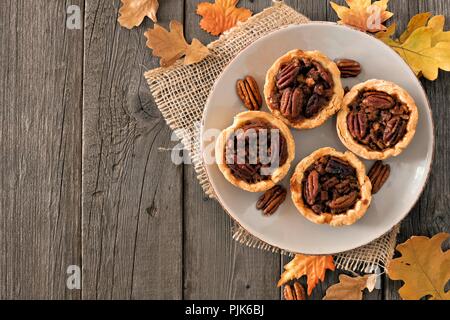 Platte von mini Pecan Pie Torten, rustikalen overhead Tabelle Szene auf einem Holz Hintergrund Stockfoto