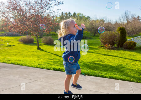 Kaukasische Kleinkind spielen mit Seifenblasen im Freien Stockfoto