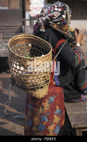 Ein Hmong Frau, die traditionelle Kopfbedeckung der Hmong und Kleidung trägt einen Korb Essen vom Markt in der Landschaft von Laos zu sammeln. Stockfoto