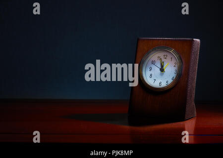 Alte Business Desk Clock auf Holztisch in der Nacht mit der Zeit fast Mitternacht, blau Ton Hintergrund zu zeigen, bei Nacht mit Kopie Raum, gute Stockfoto