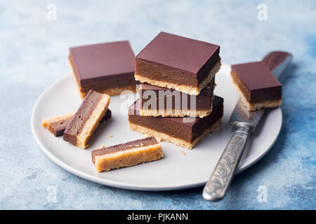 Schokolade Karamell Schichten, Bars, Millionäre shortbread auf einem grauen Platte. Blauen Hintergrund. Nahaufnahme Stockfoto