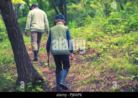 Ein Mann und eine junge Pilze im Wald sammeln. Wildlife aktive Erholung Tourismus Stockfoto