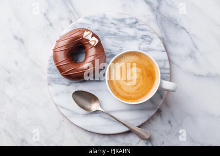 Kaffee in eine weiße Tasse mit chcolate Donut auf Marmor. Ansicht von oben Stockfoto