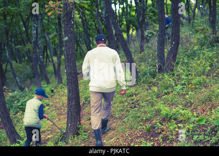 Ein Mann und eine junge Pilze im Wald sammeln. Wildlife aktive Erholung Tourismus Stockfoto