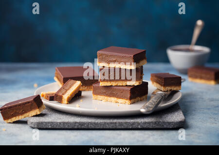 Schokolade Karamell Schichten, Bars, Millionäre shortbread auf einem grauen Platte. Blauer Hintergrund Stockfoto