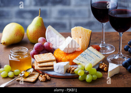Auswahl an Käse, Trauben mit roten Wein in Gläsern. Holz- Hintergrund Stockfoto