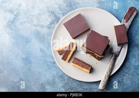 Schokolade Karamell Schichten, Bars, Millionäre shortbread auf einem grauen Platte. Blauen Hintergrund. Ansicht von oben Stockfoto